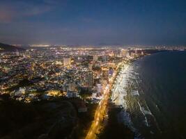 Panoramic coastal Vung Tau view from above, with waves, coastline, streets, coconut trees, Mount Nho in Vietnam behind the statue of Christ the King photo