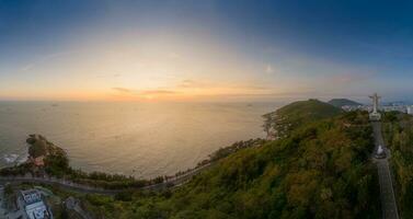 Panoramic coastal Vung Tau view from above, with waves, coastline, streets, coconut trees, Mount Nho in Vietnam behind the statue of Christ the King photo