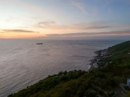 Panoramic coastal Vung Tau view from above, with waves, coastline, streets, coconut trees, Mount Nho in Vietnam behind the statue of Christ the King photo