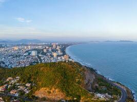 Panoramic coastal Vung Tau view from above, with waves, coastline, streets, coconut trees, Mount Nho in Vietnam behind the statue of Christ the King photo