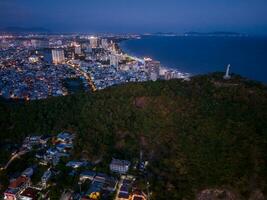 Panoramic coastal Vung Tau view from above, with waves, coastline, streets, coconut trees, Mount Nho in Vietnam behind the statue of Christ the King photo