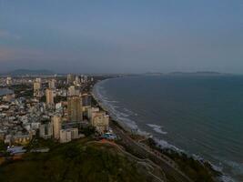 Panoramic coastal Vung Tau view from above, with waves, coastline, streets, coconut trees, Mount Nho in Vietnam behind the statue of Christ the King photo