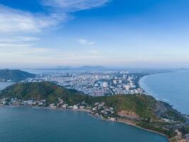 Panoramic coastal Vung Tau view from above, with waves, coastline, streets, coconut trees, Mount Nho in Vietnam behind the statue of Christ the King photo