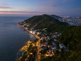 Panoramic coastal Vung Tau view from above, with waves, coastline, streets, coconut trees, Mount Nho in Vietnam behind the statue of Christ the King photo