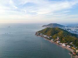 Panoramic coastal Vung Tau view from above, with waves, coastline, streets, coconut trees, Mount Nho in Vietnam behind the statue of Christ the King photo