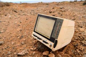 an old television sits in the middle of a desert photo