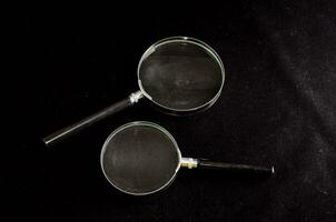 two magnifying glasses on a black surface photo