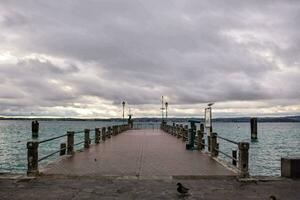 a pier with a bird on it and a cloudy sky photo