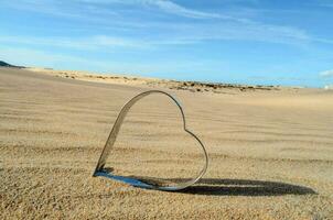 a heart shaped cookie cutter in the sand photo