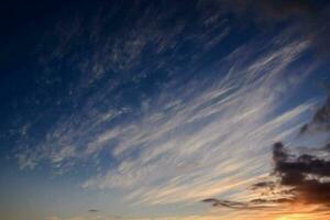 the sun sets over the ocean and clouds photo