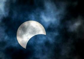 el Luna es visto durante un parcial solar eclipse en el cielo foto