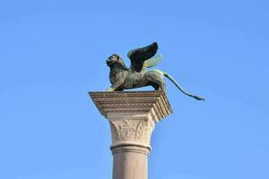 a statue of a lion with wings on top of a column photo