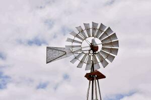 a windmill with a metal pole and a white sky photo