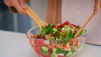 Woman mixing salad with wooden spoons for healthy meal in kitchen. Cooking preparing healthy organic food happy together lifestyle. Cheerful meal in family with vegetables photo