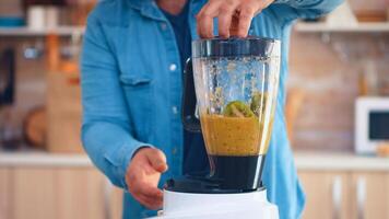 Man mixing fruits with blender for tasty smoothie in kitchen. Cheerful family making together organic healthy fresh nutritious tasty juice for breakfast from fresh fruits while on a diet. photo