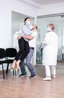 Excited young couple after receiving good from doctor with face mask in hospital waiting area. Positive man and woman in clinic after good test results. photo