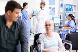 Doctor using tablet pc with patient x-ray while discussing with nurse in hospital hallway. Doctor wearing white coat and stethoscope. Health care system medical diagnosis disease teamwork photo