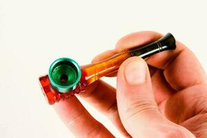 a hand holding a small pipe with a green and red tip photo
