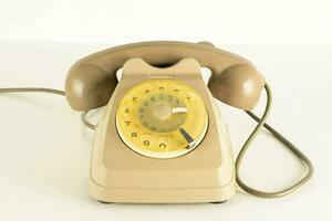 un antiguo pasado de moda teléfono en un blanco superficie foto