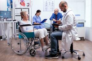 Nurse talking with disabled man in hospital room during consultation. Man with disabilities ,walking frame sitting in hospital bed. Health care system, clinic patients. photo