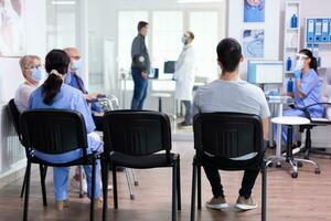 Man waiting for consultation in hospital corridor during coronavirus epidemic.. Social distancing, medic, covid-19, man, worried, protection, corona, medicine, medical, nurse, talking, virus. photo