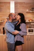 Couple feeling good while dancing in kitchen during dinner. Happy in love couple dining together at home, enjoying the meal, smiling, having fun, celebrating their anniversary. photo