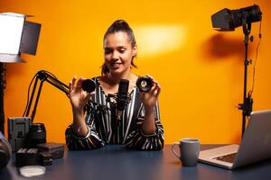 Holding nd filter and camera lens while filming podcast in home studio. New media star influencer on social media talking video photo equipment for online internet web show