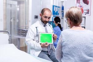 Doctor with green screen tablet in front of elderly patient explaining medical diagnosis. Ready chroma mockup for your app, text, video or other digital asset photo