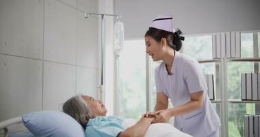 Portrait of Young nurse comforting a senior female patient lying in hospital bed,Caregiver and Lifestyle concept photo