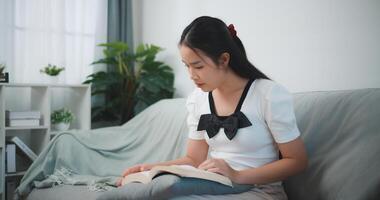 Portrait of Young asian woman sitting relaxing on couch and reading book in living room,spending leisure time at home. photo