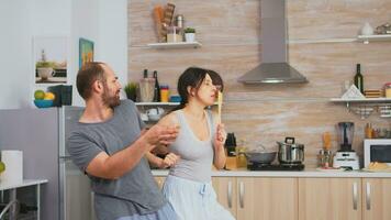 Authentic couple dancing in pajamas holding kitchenware during breakfast. Carefree wife and husband laughing having fun funny enjoying life authentic married people positive happy relation photo