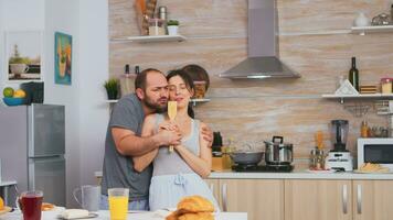 esposa canto en de madera cuchara mientras bailando con marido en cocina vistiendo pijama. despreocupado Pareja riendo teniendo divertido gracioso disfrutando vida auténtico casado personas positivo contento relación foto