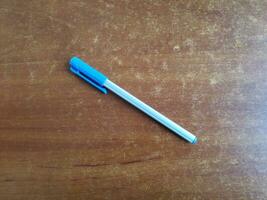 AI generated blue pen on the wooden table background, top view with copy space photo