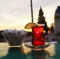 AI generated Turkish tea in a glass on a table in a cafe at sunset photo