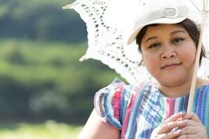 retrato de asiático exceso de peso mujer viaje en flor campo en verano foto