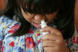 close up of sick child using nasal medicine spray photo