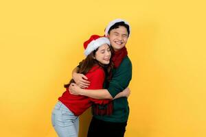 Asian couple wearing colorful Christmas sweaters and hats happily hugs each other. photo