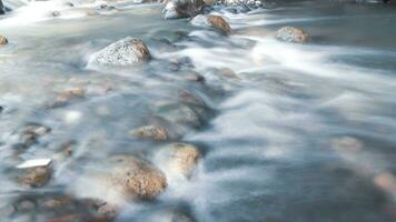 close up of water flowing over cobblestone in river photo