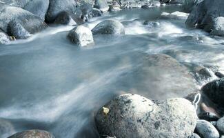 close up of water flowing over cobblestone in river photo