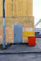 yellow wall of building and red street dumpster photo