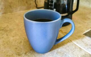 Blue coffee cup and black coffee maker from Mexico. photo