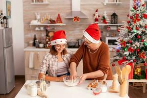 niño mezcla galletas ingredientes en cuenco haciendo tradicional hecho en casa masa con abuela celebrando Navidad fiesta juntos en Navidad decorado cocina. niño disfrutando invierno temporada horneando postre foto