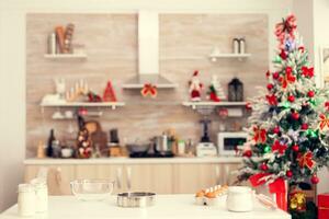 Ingredients for delicious cookies on christmas day on empty room. Kitchen on christmas day with nobody in the room decorated with x-mas tree and garlands photo