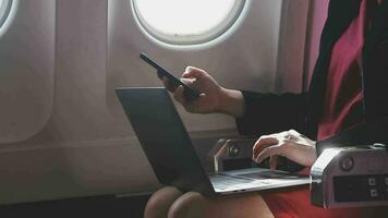 asiatisk ung kvinna använder sig av bärbar dator Sammanträde nära fönster på först klass på flygplan under flyg, resor och företag begrepp video