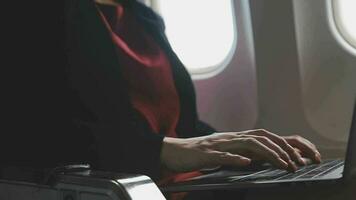 Aziatisch jong vrouw gebruik makend van laptop zittend in de buurt ramen Bij eerste klasse Aan vliegtuig gedurende vlucht, reizen en bedrijf concept video