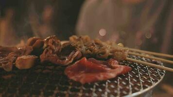 Party for barbecue japanese style, yakiniku. Meats are being cooked on stove in a japanese video