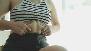 mujer gorda, barriga gorda, gordita, mujer obesa mano sosteniendo grasa abdominal excesiva con cinta métrica, concepto de estilo de vida de dieta de mujer video