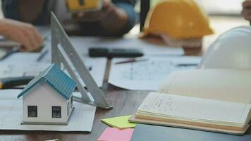 mani di architetto o ingegnere Lavorando su planimetria incontro per progetto Lavorando con compagno su modello edificio e ingegneria utensili nel Lavorando luogo, costruzione e struttura concetto. video