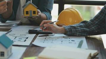 mani di architetto o ingegnere Lavorando su planimetria incontro per progetto Lavorando con compagno su modello edificio e ingegneria utensili nel Lavorando luogo, costruzione e struttura concetto. video