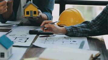 mani di architetto o ingegnere Lavorando su planimetria incontro per progetto Lavorando con compagno su modello edificio e ingegneria utensili nel Lavorando luogo, costruzione e struttura concetto. video